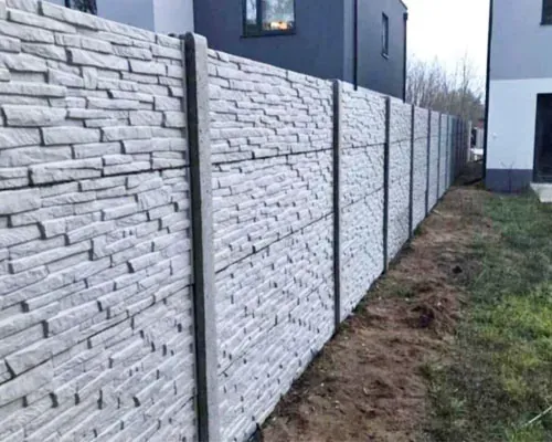 Előregyártott kőmintás betonkerítés beton oszlopokkal hosszú telekhatáron